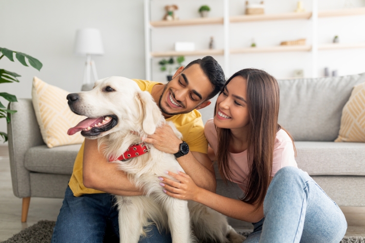 A happy couple in their house hugging their dog